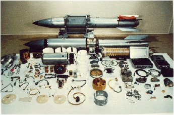 A B61 nuclear bomb shown assembled at the back and disassembled into components in the foreground.